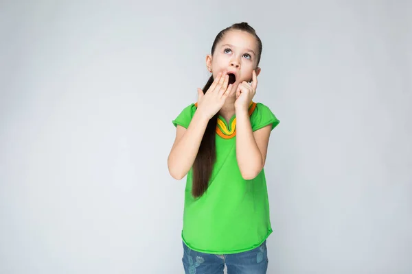 The girl on a gray background yawns and covers her mouth with her hand. — Stock Photo, Image