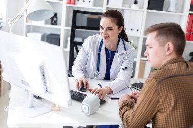 Doktor hastaya bilgisayarda sorunu anlatan.