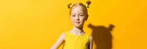 Chica con el pelo rojo sobre un fondo amarillo. La chica sostiene un globo de aire amarillo . —  Fotos de Stock