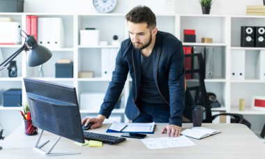 Genç adam tablo yakınındaki ofiste standları ve ekrana görünüyor.
