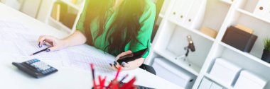 Ofiste gözlüklü genç bir kız ellerini ve gülümser bir telefon tutar.