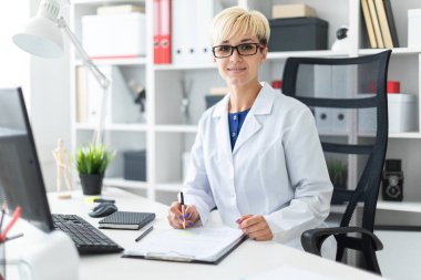 Güzel bir genç kız bir bilgisayar Resepsiyon parlak bir ofiste çalışan beyaz bir elbise içinde. Önce tablo üzerinde belge yatıyor. Kız kısa beyaz saç ve gözlük vardır. alan derinliği ile fotoğraf