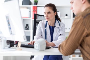 Doktor hastaya bilgisayarda sorunu anlatan.