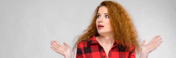 A girl in a plaid shirt spreads her arms out to the sides. Young girl with red hair — Stock Photo, Image