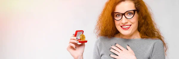 灰色の背景に cryptocurrency 概念として bitcoin を示すガラスの灰色の服を着て美しい赤毛幸せ笑顔の若い女性の肖像画 — ストック写真