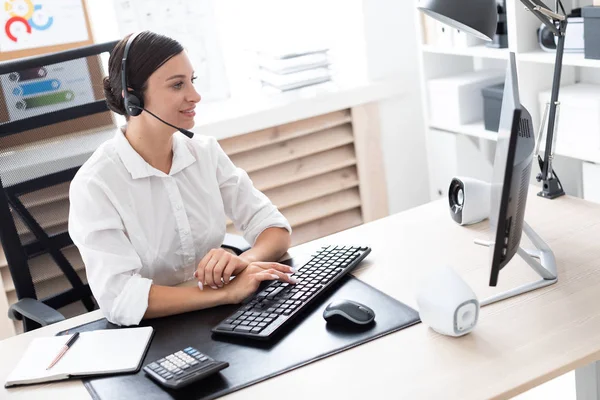 A young girl in headphones with a microphone sitting at a computer table. — Stock Photo, Image