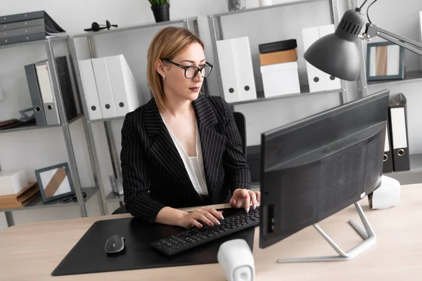 A young girl working at a computer in the office.