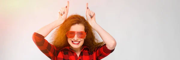 Retrato de bela ruiva feliz jovem mulher em óculos sorrindo enganando no fundo cinza — Fotografia de Stock