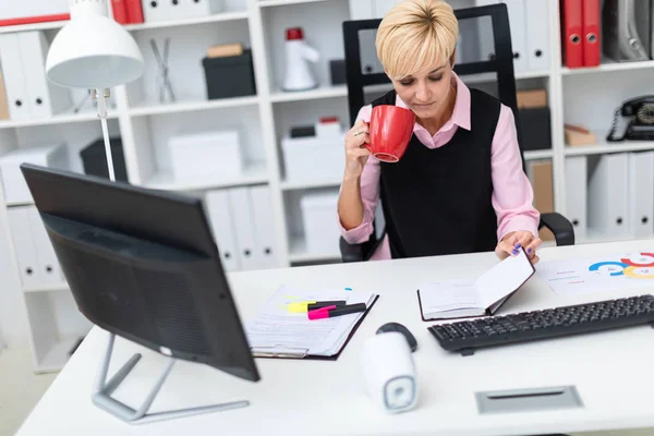 Chica sentada en la oficina en la mesa y tomando café . — Foto de Stock