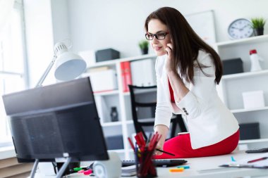 Ofis ve works belgeleri ve bir bilgisayar ile bir masa üzerine bir genç kız oturdu.