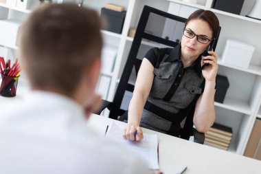 Gençler bilgisayar tablo ve belgelerle çalışma ofisinde oturup. Telefonla arama kız.