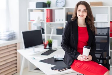 Genç bir kız ofis ve bir bardak kahve tutan bir masada oturdu.