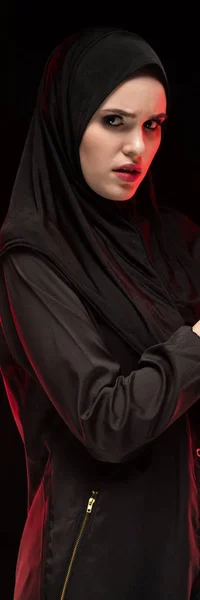 Portrait of beautiful serious scared young muslim woman wearing black hijab calling for help on black background — Stock Photo, Image