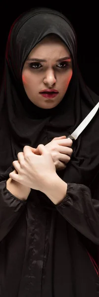 Porträt der schönen verzweifelten verängstigten jungen Muslimin mit schwarzem Hijab und Messer in der Hand als Schutzkonzept auf schwarzem Hintergrund — Stockfoto