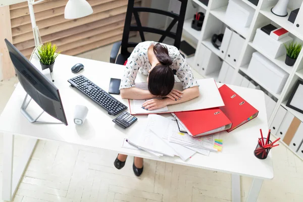 Uma jovem sentada em uma cadeira de escritório em uma mesa de computador e colocar a cabeça sobre a mesa . — Fotografia de Stock