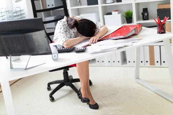 Una joven sentada en una silla de oficina en una mesa de computadora y puso su cabeza sobre la mesa . — Foto de Stock