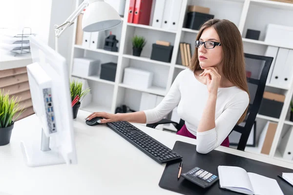 Een jong meisje, zittend aan een tafel en te typen op het toetsenbord. — Stockfoto