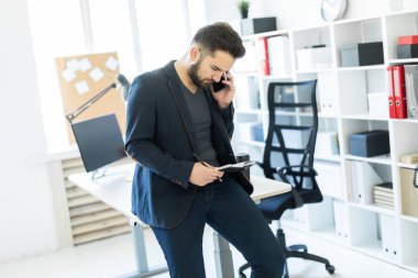 Ofis ve telefonda konuşurken bir masada oturdu genç adam.