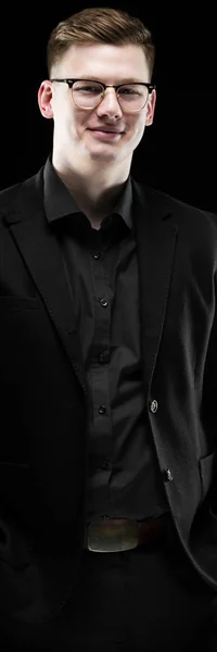 Portrét jistý pohledný elegantní zodpovědný podnikatel v brýlích s rukama v kapsách na černém pozadí — Stock fotografie