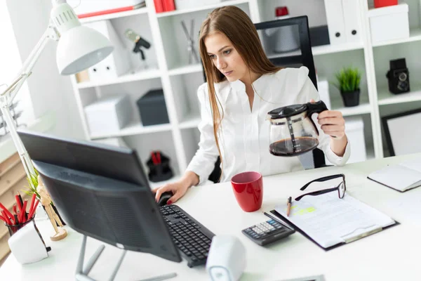Молодая девушка сидит за компьютером в офисе и наливает ему кофе . — стоковое фото