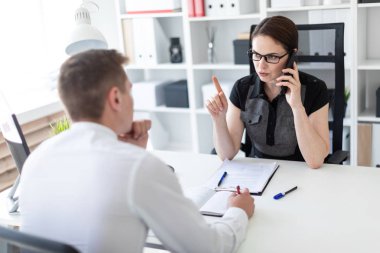 Gençler bilgisayar tablo ve belgelerle çalışma ofisinde oturup. Telefonla arama kız.