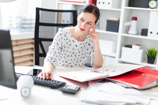 Een jong meisje zittend op kantoor op de computer Desk, werken met documenten en houden handen op zijn hoofd. — Stockfoto