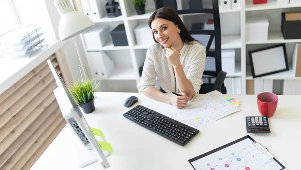 Een jong meisje werken in het kantoor met documenten en een computer. Portret van een jong meisje aan tafel. — Stockfoto