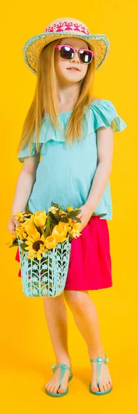 Chica con el pelo rojo sobre un fondo amarillo. Una chica encantadora con ropa de verano brillante sostiene una canasta de girasoles en sus manos . —  Fotos de Stock