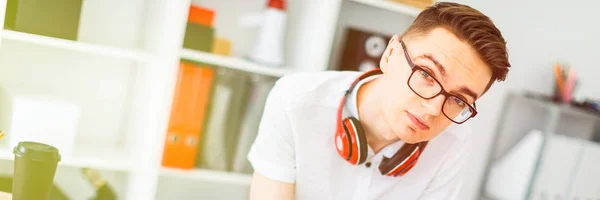 Un joven con gafas está cerca de un escritorio de computadora. Un joven dibuja un marcador en una pizarra magnética. En el cuello, los auriculares de los chicos cuelgan . — Foto de Stock