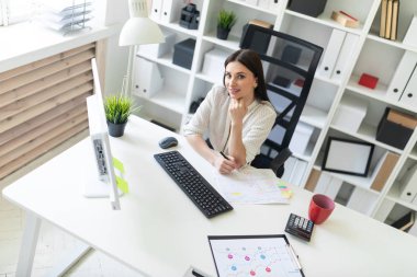 Office belgeleri ve bir bilgisayar ile çalışan bir genç kız. Masada genç bir kızın portresi.