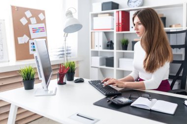 Bir genç kız bir masada oturan ve klavyede yazarak.