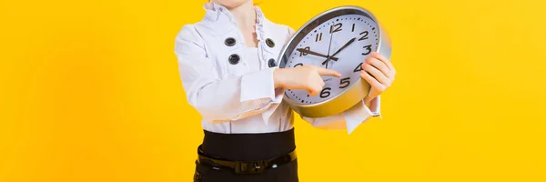 Mädchen mit roten Haaren auf gelbem Hintergrund. ein charmantes Mädchen mit durchsichtiger Brille hält eine Uhr. — Stockfoto