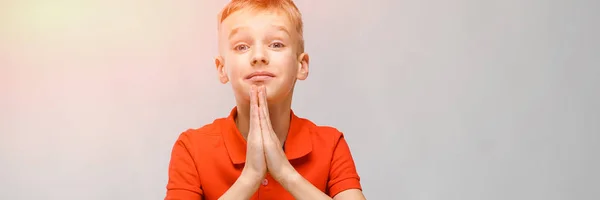 Retrato de lindo niño rubio caucásico en camiseta naranja con la esperanza de fondo gris —  Fotos de Stock