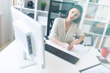 Office belgeleri ve bir bilgisayar ile çalışan bir genç kız. Masada genç bir kızın portresi.