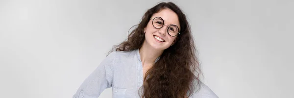 Retrato de uma jovem menina feliz em óculos. Menina bonita em um fundo cinza. Uma menina em uma blusa leve e calças escuras . — Fotografia de Stock