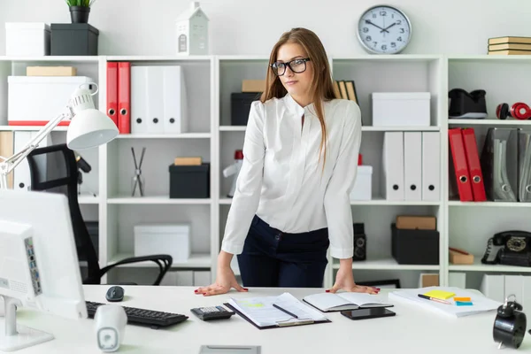 Een jong meisje dat permanent in de buurt van de tabel in het kantoor. — Stockfoto