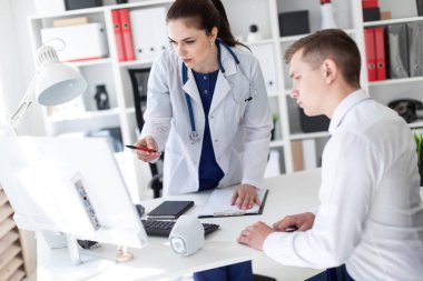 Doktor hastaya bilgisayarda sorunu anlatan.