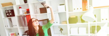 Bir genç kız bardaklarda Office masada oturur ve kendini telefon çekiyor.