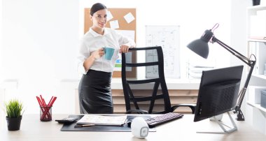 Ofiste duran ve bir fincan tutan genç bir kız.