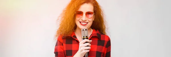 Mujer atractiva en gafas con micrófono —  Fotos de Stock