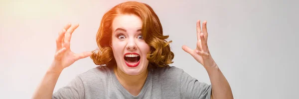 Charming young girl in a gray T-shirt on a gray background. The girl screams — Stock Photo, Image