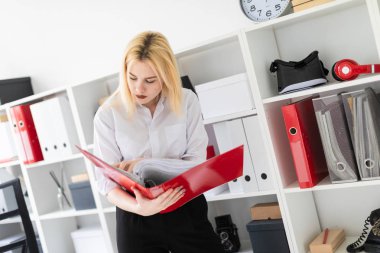 Ofiste duran ve bir klasör tutan genç bir kız.