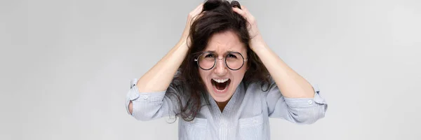 Young brunette girl with glasses. The girl grabbed her head and shouted. — Stock Photo, Image