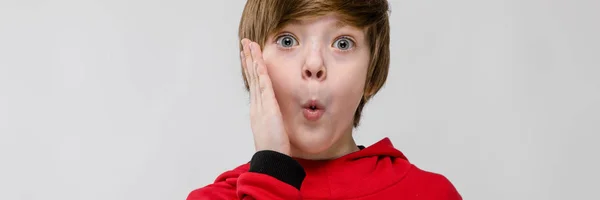 Jistý bělošský roztomilé překvapení chlapce v červený svetr na šedém pozadí — Stock fotografie