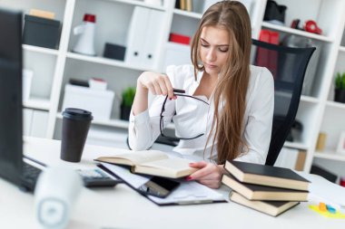 Kitap ve belgeler ile ofiste çalışan bir genç kız.