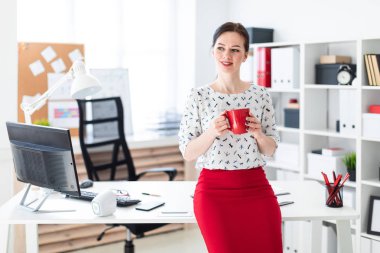 Bir bilgisayarda Resepsiyon ofis ve kırmızı bir fincan tutan genç bir kız oturdu.