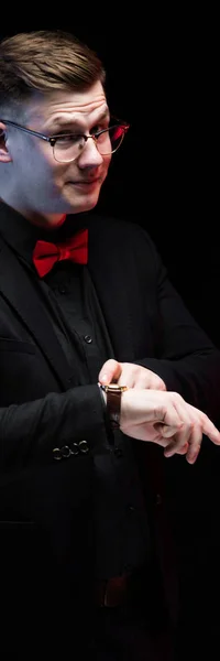 Retrato de confiante bonito elegante homem de negócios responsável com a mão em seu relógio no fundo preto — Fotografia de Stock