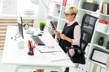 Resepsiyon bir bilgisayar başında oturan ve bir telefon ve bir banka kartı tutan genç bir kız.