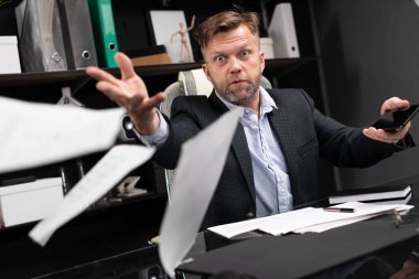 Öfkeli işadamı belgeleri iletme ofise atar.