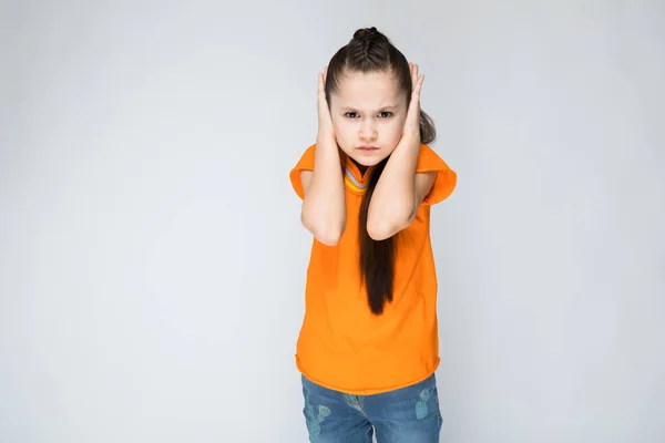 Girl on a gray background put her hands over her ears. — Stock Photo, Image